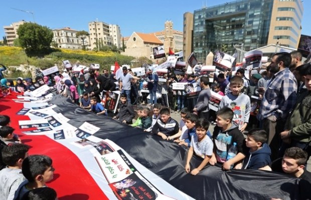 Lebanese children hold placards and a giant Yemeni flag during a demonstration organized by Hezbollah, in front the United Nations headquarters in Beirut, Lebanon, Sunday, April 5, 2015. (AP Photo/Bilal Hussein)